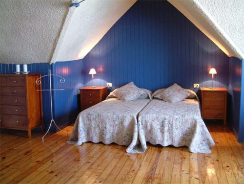 a bedroom with a bed with blue walls and wooden floors at As Casiñas in Ribadavia