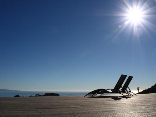 a pair of chairs sitting on a beach with the sun at Parautane Lodge in Nelson