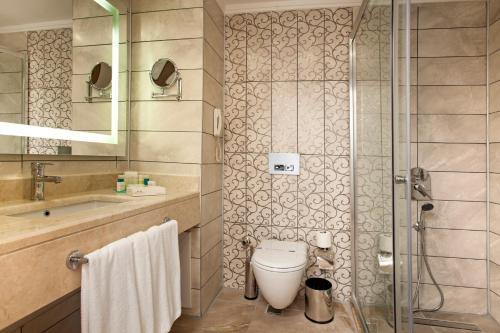 a bathroom with a shower and a toilet and a sink at Luna Blanca Resort & Spa in Side