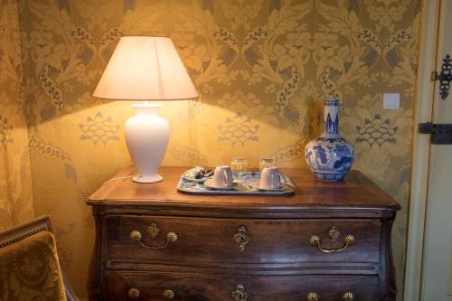 a lamp on top of a wooden dresser with a table with mugs at Chambres d'hôtes au Château de Gizeux in Gizeux