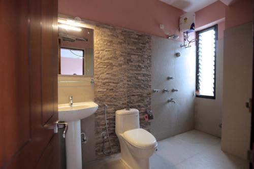 a bathroom with a white toilet and a sink at Yaksha Holiday Home in Siliguri