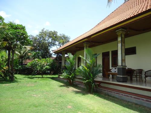 a house with a porch and a grass yard at Pande Homestay in Canggu