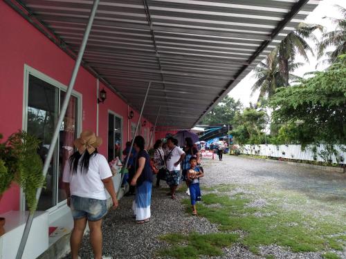 a group of people walking under awning next to a red building at Saan Rak Resort in Prachuap Khiri Khan