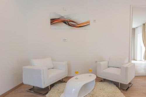 uma sala de estar com duas cadeiras e uma mesa em Rooms Sea & Sun with private parking em Zadar