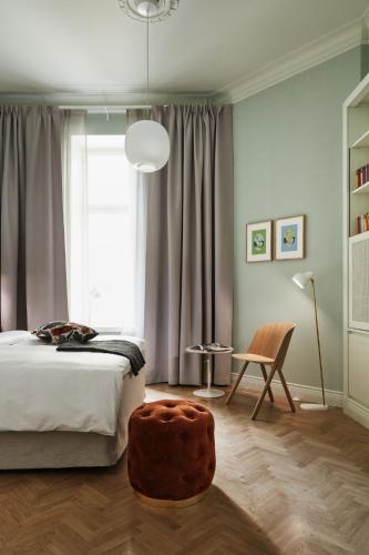 a bedroom with a bed and a chair and a window at Hotel St. George Helsinki in Helsinki