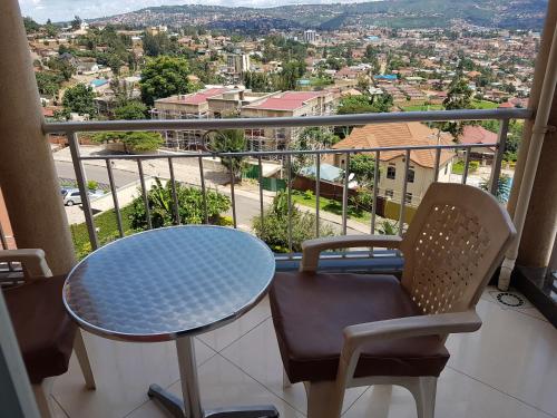 a table and chairs on a balcony with a view of a city at Beausejour Hotel in Kigali