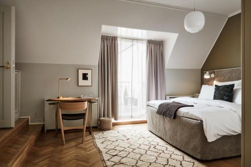 a bedroom with a bed and a desk and a window at Hotel St. George Helsinki in Helsinki