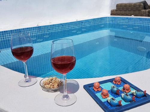 two glasses of wine and a tray of food next to a swimming pool at Aqua & Terra Traditional Cave Houses in Oia