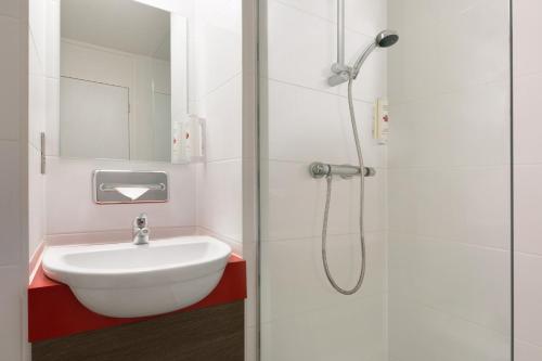 uma casa de banho branca com um lavatório e um chuveiro em Ramada Chorley South em Chorley