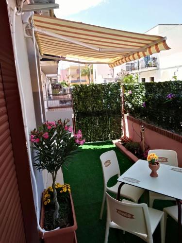 a patio with a table and chairs and an umbrella at Holiday House Marlin in Giardini Naxos