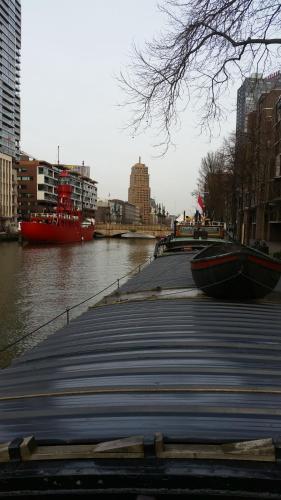 a dock next to a river with a large boat at Houseboat holiday apartments Rotterdam in Rotterdam