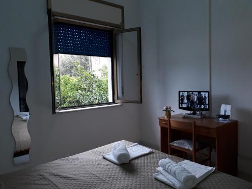 a bedroom with a bed and a desk and a window at Pensione Nettuno in Palinuro