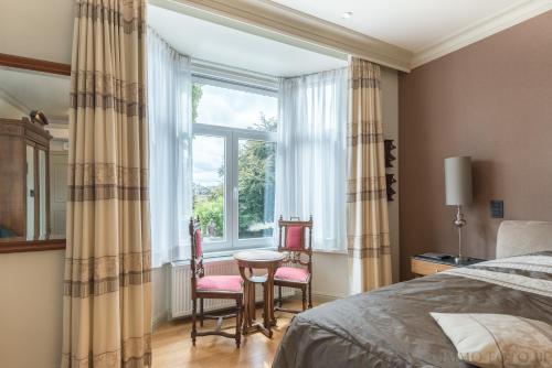 a bedroom with a bed and two chairs in front of a window at Dendernachten in Dendermonde