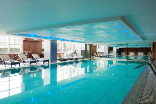 The Chelsea Harbour Hotel and Spa في لندن: مسبح في الفندق مع الكراسي والطاولات