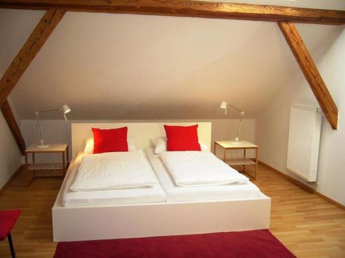 a white bed with red pillows in a room at Ferienwohnungen Schönbachtal in Drachselsried
