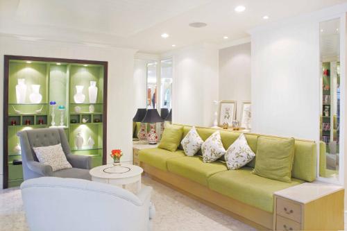 a living room with a green couch and chairs at La Petite Salil Sukhumvit Thonglor 1 in Bangkok