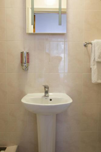 a bathroom with a white sink and a mirror at Abbey Court Hotel - Hyde Park in London