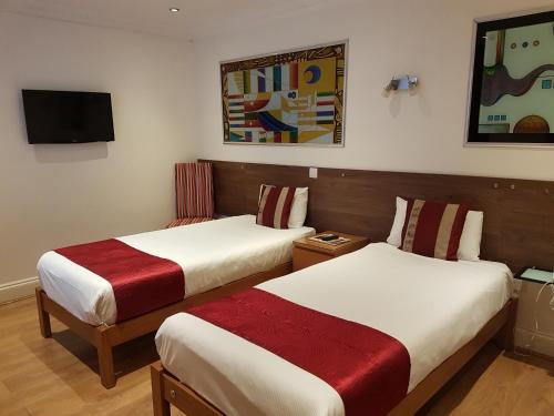 a hotel room with two beds and a tv at Abbey Court Hotel - Hyde Park in London