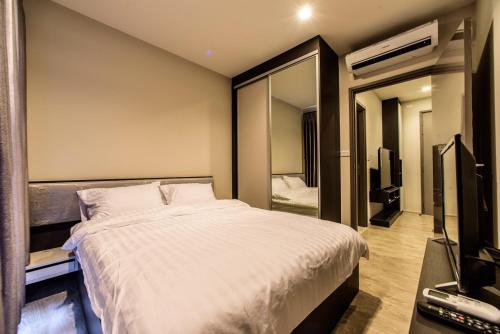 Un dormitorio con una gran cama blanca y un espejo. en The BASE Central Pattaya by NKL, en Pattaya central