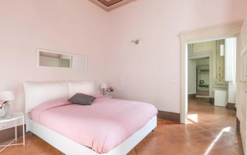 een witte slaapkamer met een bed met een roze deken bij siena centro, civetta in Siena