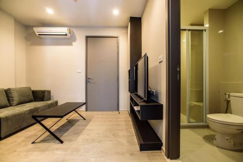 Una pequeña sala de estar con un sofá y un televisor. en The BASE Central Pattaya by NKL, en Pattaya central
