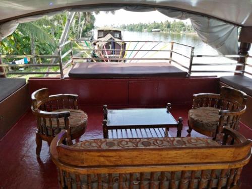a boat with two chairs and a bed on the back at Vaishnav Tours in Alleppey