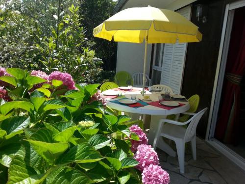 une table avec un parapluie jaune et quelques fleurs dans l'établissement Villa 