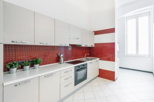 a kitchen with white cabinets and a red tile wall at mrg home holiday in Sorrento