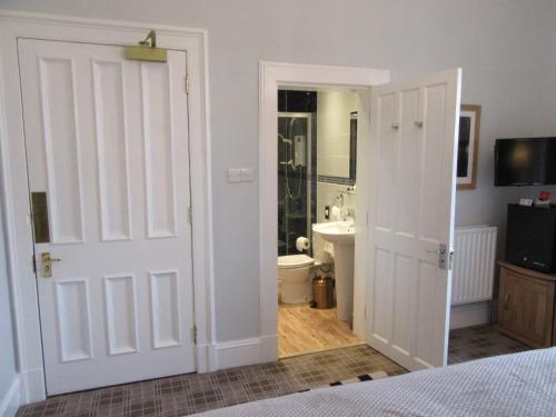 a bedroom with a door leading to a bathroom at Middleton House Bed and Breakfast in Auchterarder