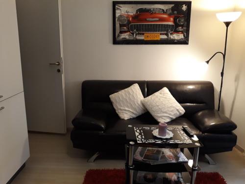 a living room with a black leather couch and a table at Apartments Paris in Umag