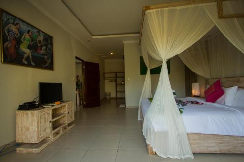 a bedroom with a bed with a net canopy at Ratna Villa in Ubud