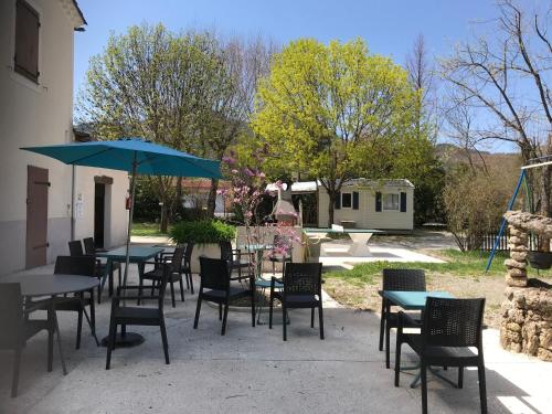 a group of tables and chairs with blue umbrellas at Camping Frédéric Mistral in Castellane