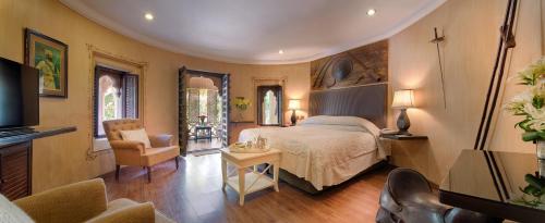 a bedroom with a bed and a chair and a television at Ajit Bhawan - A Palace Resort in Jodhpur