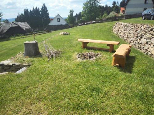 a wooden bench sitting in the grass in a field at Javorník 88 in Javorník