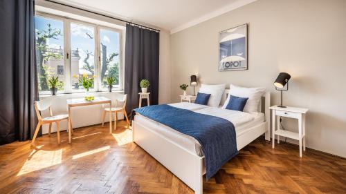 a white bedroom with a bed and a desk and a window at Fenna Apartments 7 minut od Rynku in Krakow