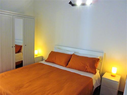 a bedroom with a bed with orange pillows and two lamps at icalderai in Palermo