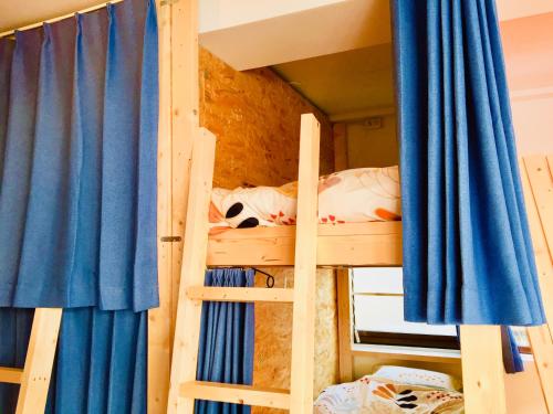 two bunk beds in a room with blue curtains at Cloud Sharing Hotel Hakata 1 Guesthouse Dormitory in Fukuoka