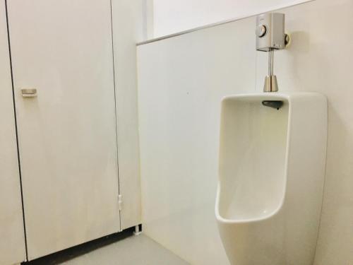 a urinal in a bathroom with a white wall at Cloud Sharing Hotel Hakata 1 Guesthouse Dormitory in Fukuoka