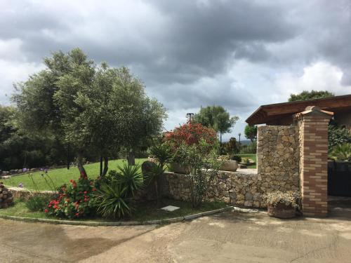 a garden with a stone wall and trees and flowers at Hotel Belvedere in Teulada