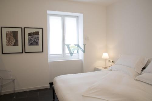 ein weißes Schlafzimmer mit einem großen Bett und einem Fenster in der Unterkunft Villa Navalia in Menaggio