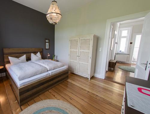 um quarto com uma cama, pisos em madeira e um lustre em Seaside Apartments Austernbank em Cuxhaven