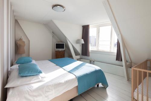 a bedroom with a bed with blue pillows and a window at Hotel Grand Cafe Deight in Zandvoort