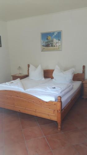 a wooden bed with white sheets and pillows on it at Motel Route 216 in Göhrde