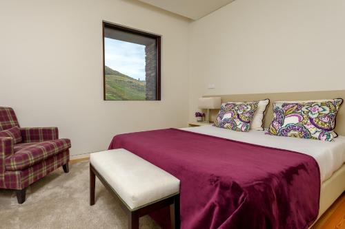 een slaapkamer met een bed, een stoel en een raam bij Quinta de Merouço - Villa do Rolapipas in Alijó