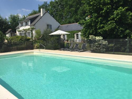 a large blue swimming pool in front of a house at La Butte de Gohier in Blaison