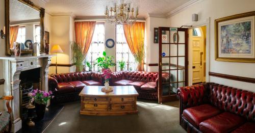 a living room with leather couches and a coffee table at Pymgate Lodge Hotel Manchester Airport in Cheadle