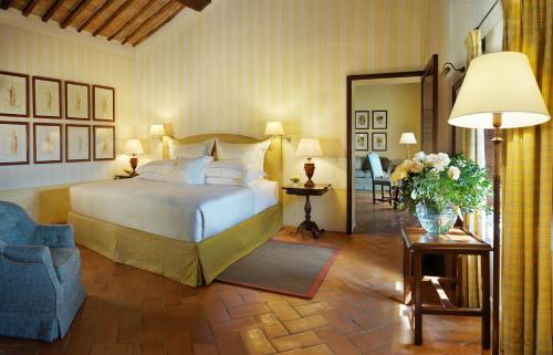 a bedroom with a bed and a chair and a mirror at Castello Banfi - Il Borgo - Relais et Chateaux in Montalcino