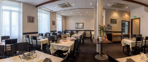 Hôtel Montfort في لورد: غرفة طعام مع طاولات بيضاء وكراسي وطاولة
