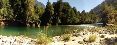 a river with a bunch of rocks and trees at La Frontera Bed & Breakfast, Valle Cochamó in Cochamó