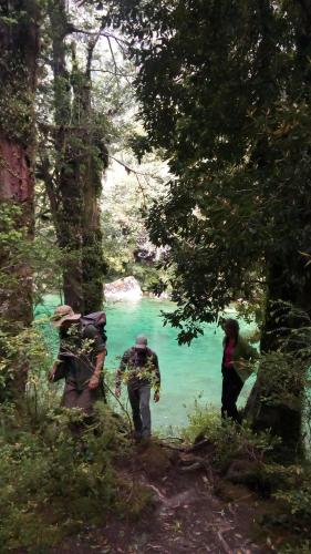 a group of people walking down a trail near a river at La Frontera Bed & Breakfast, Valle Cochamó in Cochamó